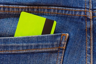 A plastic discount card or a light green bank card in the pocket of blue jeans