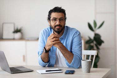 Millennial Freelancer. Portrait Of Young Arab Man At Desk In Home Office