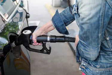 Woman's hand with gloves holding hose from gas pump