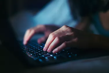 Close-up Shot Of Young Woman Working Late With Laptop In The Dark