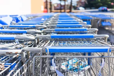 Many rows of blue shopping carts outside by store with closeup by parking lot