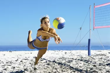 Female playing beach volleyball diving to catch ball