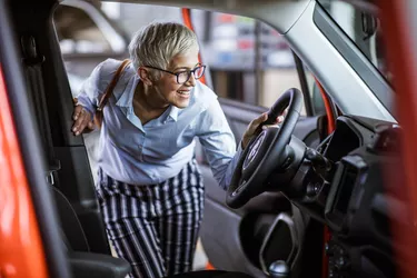 Happy woman buying a car in a showroom.