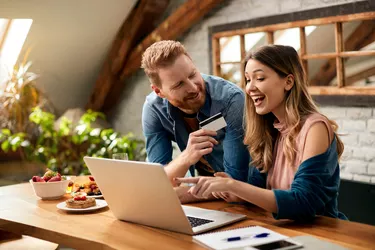 Happy couple having fun while online shopping at home.