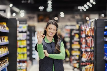 A happy female manager gesturing with okay sign and smiling at the camera at supermarket.