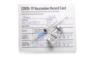 Covid-19 vaccination record card with syringe and vial