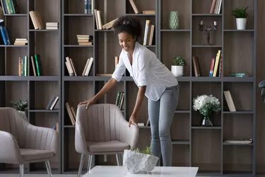 Smiling African American woman tenant renter decorating modern apartment