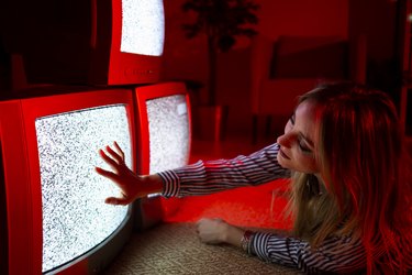 Young woman touching vintage TV screen while lying on front at home