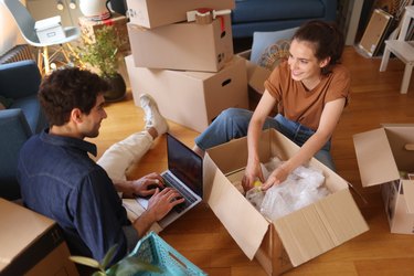 A young couple packing/unwrapping moving boxes