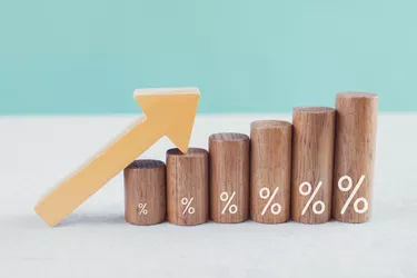 Wooden blocks with percentage sign and arrow up, financial growth, interest rate and mortgage rate increase, inflation concept