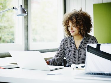 Smiling businesswoman working on project on laptop