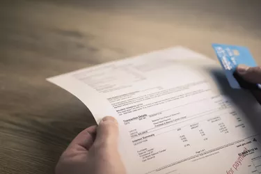 Mans hands holding credit card and bill at table