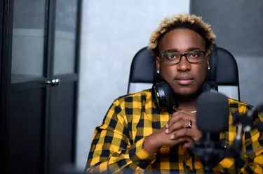 Radio host sitting before a microphone.