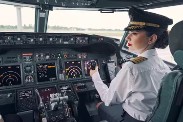 Pensive dark-haired woman co-pilot seated in the cockpit