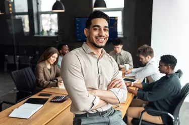 Young bearded businessman sitting on desk and posing