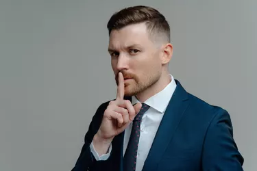 Serious businessman in suit showing silence sign