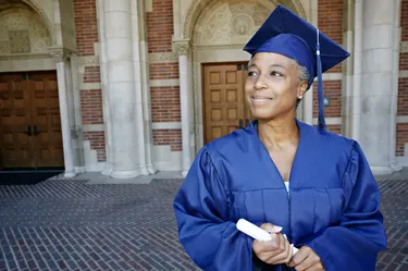 Smiling Black woman holding graduation diploma