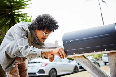 Young man standing outside and checking his mailbox