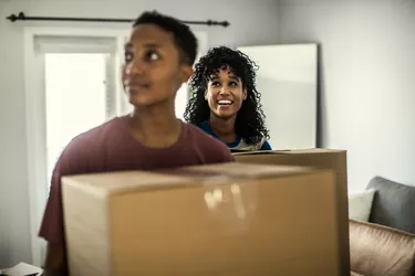 Lesbian couple carrying moving boxes into home