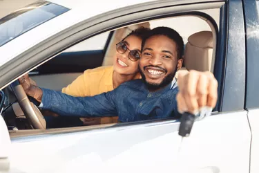 African American Spouses Showing New Car Key Sitting In Automobile