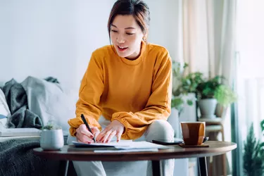 Young Asian woman holding a pen and signing paperwork