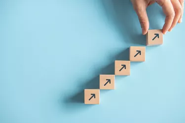 Close up arranging wood block stacking as step stair on paper pink background. Business concept growth success process, copy space.