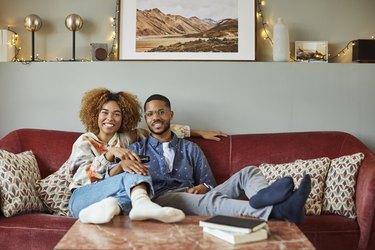 Smiling Woman With Boyfriend Watching TV At Home
