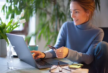 Woman checking computer with credit card in hand