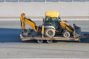 Loaded tractor with a bucket on a trailer platform.