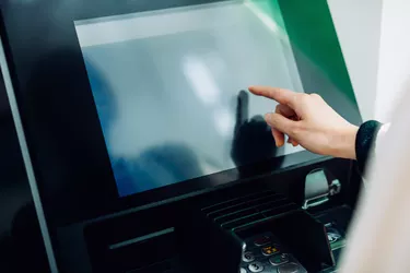 Close up of young woman using automatic cash machine in the city. Withdrawing money, paying bills, checking account balances, transferring money. Privacy protection, internet and mobile security concept