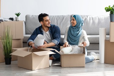 Cheerful arab family unpacking belongings, moving to new apartment