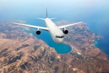 White passenger plane fly high over the sea coast