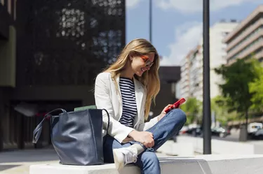 Smiling blonde business woman looking at her mobile phone