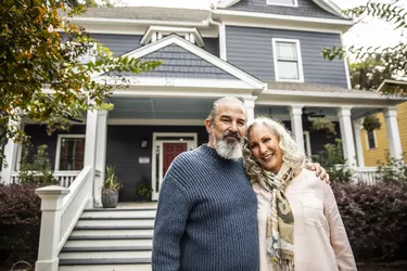 Portrait of senior husband and wife in front of suburban home