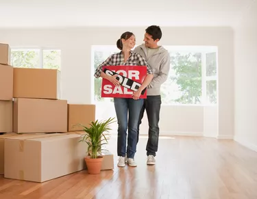 Couple holding sold sign for their new house