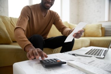 African ethnicity man calculates digits using calculator planning family budget