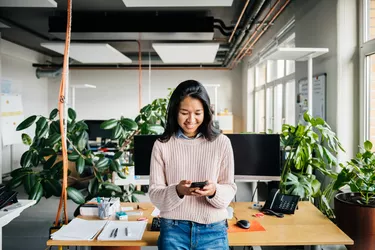 Young Office Employee Using Smartphone At Desk