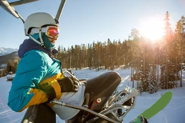 Guy with a wheelchair sled riding a chairlift.