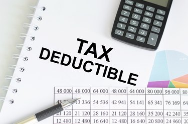Text Tax Deduction on a notepad among charts and reports on the table. Business and financial concept