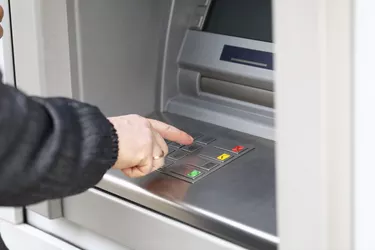 Man dials PIN code to withdraw money from ATM