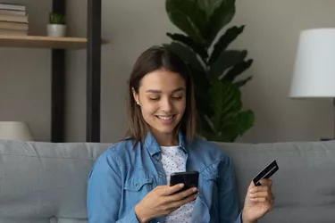 Close up smiling woman holding plastic card and phone