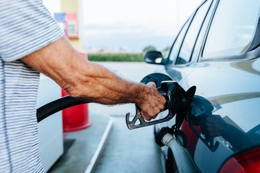 Senior man filling the tank of his car at the gas station.