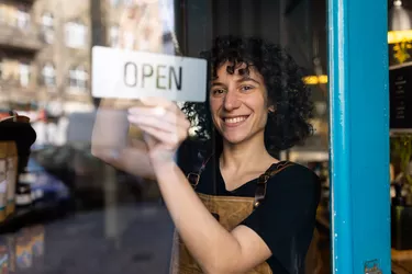 Happy non-binary business owner reopening their store