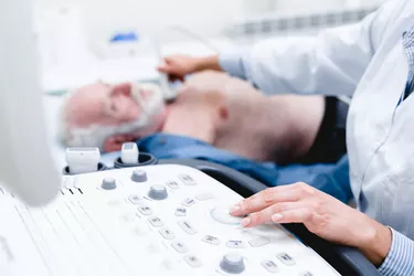 Woman doctor scanning vessels on the neck with ultrasound device scan. Selective focus