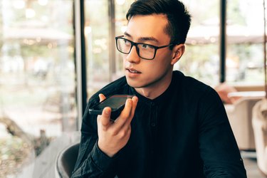 Smart and handsome Asian entrepreneur is using mobile phone to record an audio message