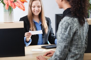 Bank Teller Serving Customer Transaction at Retail Banking Counter Window
