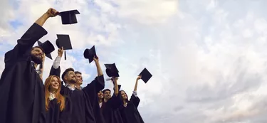 Millennial students celebrating graduation ceremony and throwing their caps up. Young people on commencement day