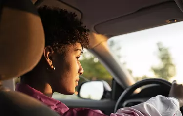 Young woman driving car during sunny day