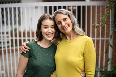 Portrait of mother and daughter in front of the house