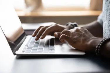 Close up African American male hands typing on laptop keyboard